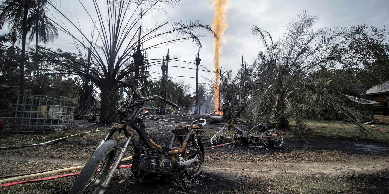 En eldhärjad motorcykel i närheten av den brinnande oljekällan i byn Pasir Putih, i Aceh-provinsen.