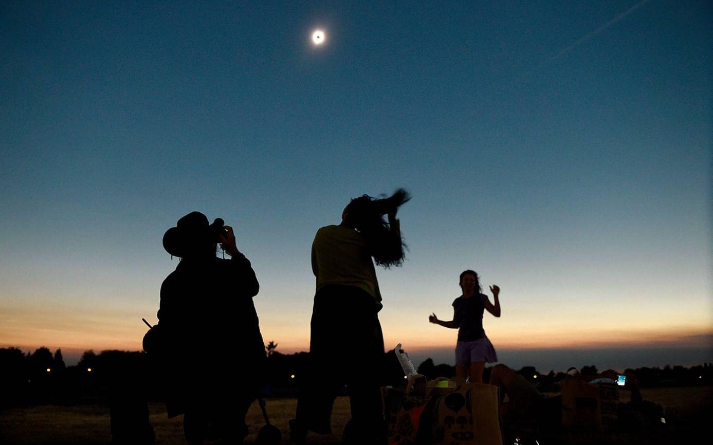 En fotograf förevigar ögonblicket när hans fru och vän dansar under solförmörkelsen i Albany. Bild: AP/TT