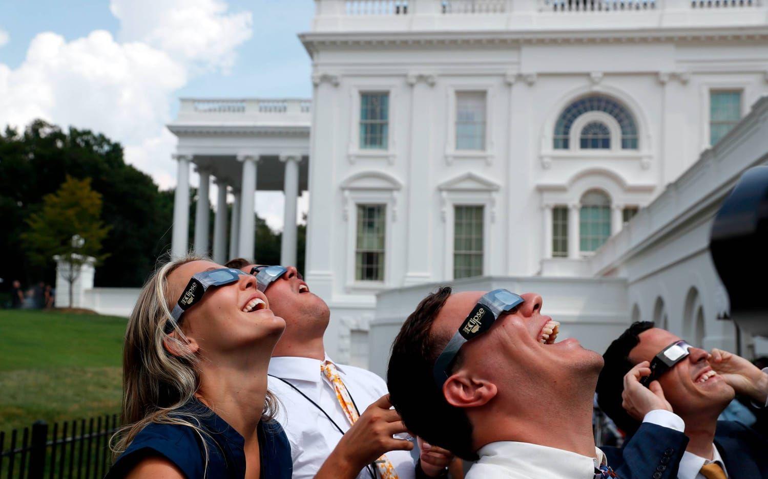 Personal utanför Vita Huset har tagit på sig skyddsglasögon för att titta på solförmörkelsen. Bild: AP/TT