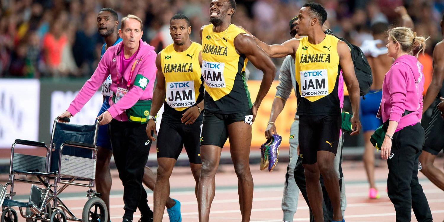 Usain Bolt haltar ut skadad från sitt sista mästerskapslopp, omgiven av sina jamaicanska lagkompisar i stafettloppet som han bröt.
