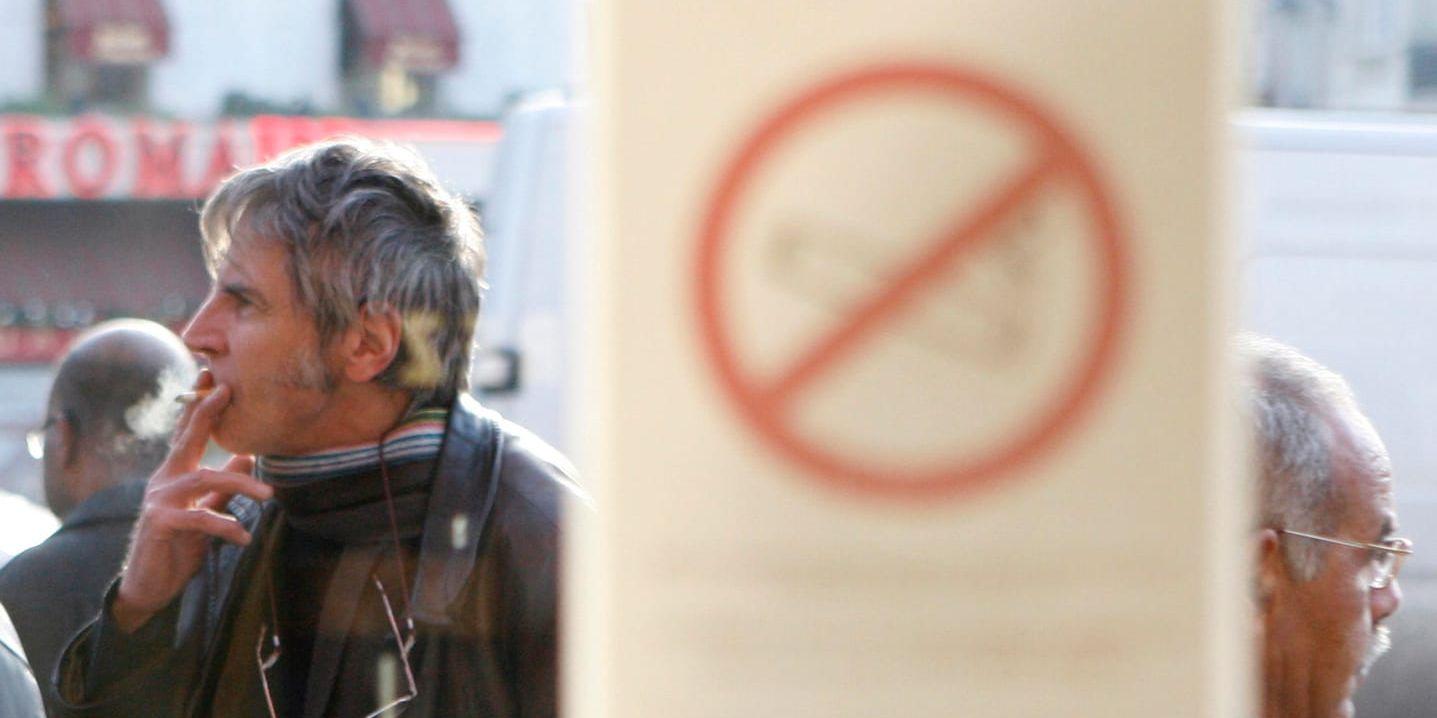 En man röker en cigarett utanför ett brasserie i Paris. Frankrike införde rökförbud på restauranger och barer 2008. Nu börjar man förbjuda tobaksrök även i parker. Arkivbild.