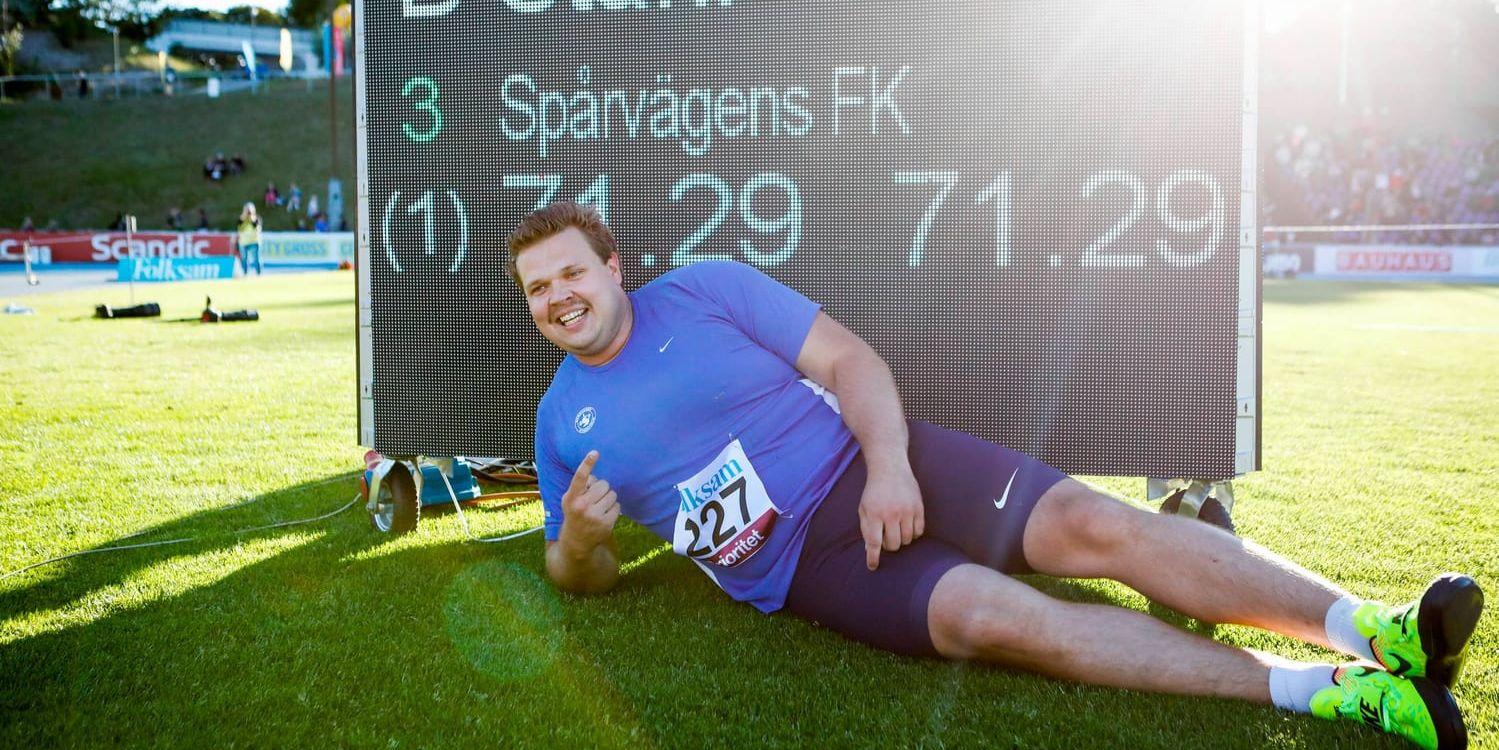 Daniel Ståhl poserar framför resultattavlan som visar det nya svenska rekordet i diskus.
