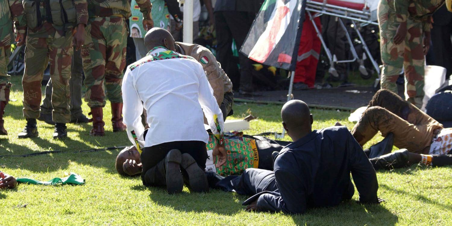 Skadade människor ligger på marken efter explosion envid ett politiskt möte i staden Bulawayo i Zimbabwe i lördags.