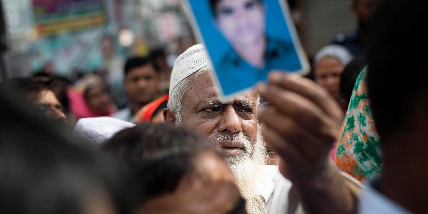 En man håller upp ett fotografi på sin son som dött när fabrikskomplexet Rana Plaza kollapsade 2013. Fem år efter tragedin kräver offer och anhöriga rättvisa.