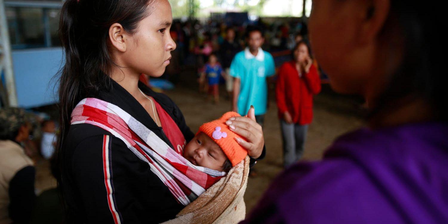En kvinna i Paksong, nära den kollapsade dammen i Laos, håller om sitt barn. Kvinnan och barnet har dock inte med artikeln att göra.