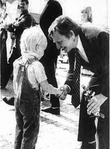 Fick partiros. När Olof Palme besökte Laholm 1984 var han utan partiros i rockuppslaget. Treåringen Niklas Olofsson reparerade skadan och gav statsministern en röd ros framför Rådhuset. Bild HP/arkiv