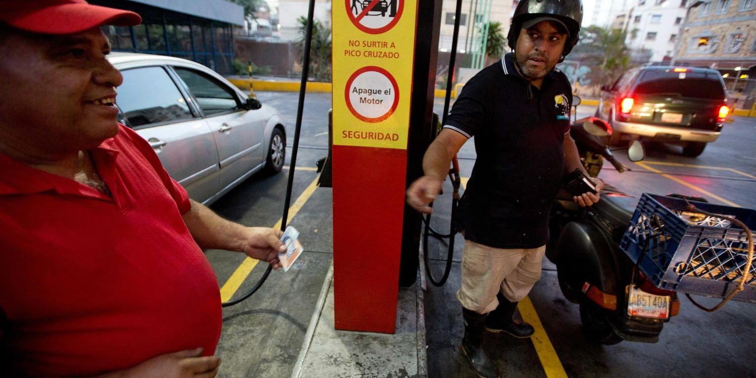 En skoterförare betalar en blygsam slant för bensin i Caracas. Arkivbild.