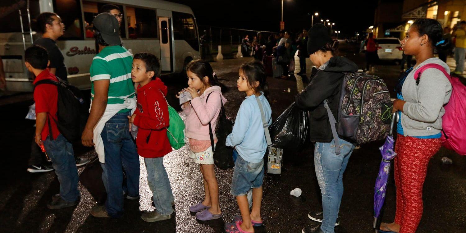 Migranter från Honduras som hoppas kunna ta sig till USA väntar på att få åka buss över gränsen till Guatemala.