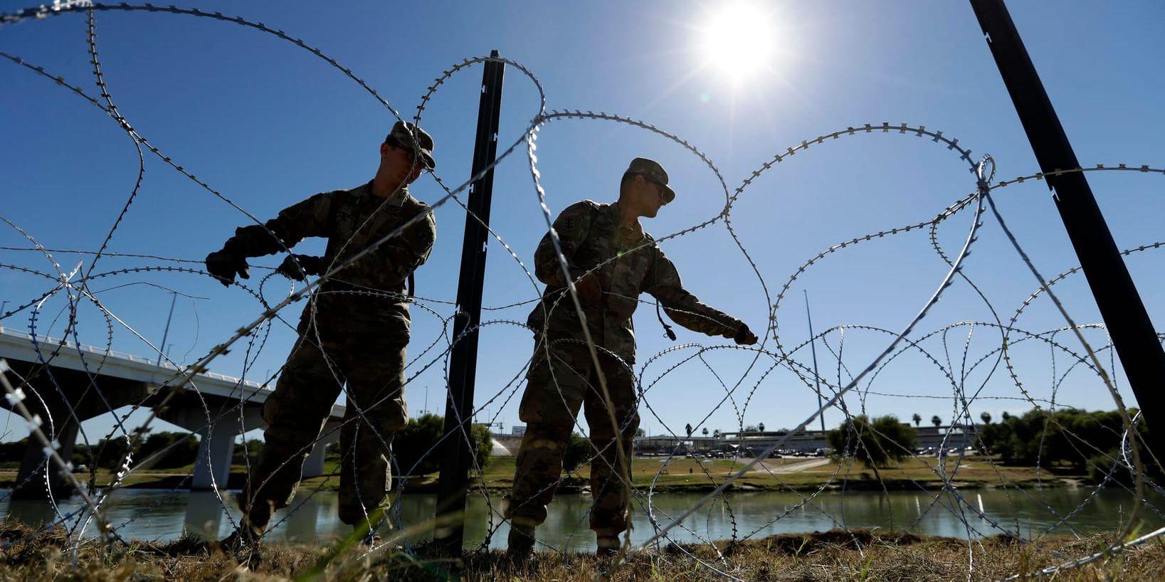 Två amerikanska soldater bygger ett stängsel av taggtråd vid gränsen mot Mexiko. Arkivbild.