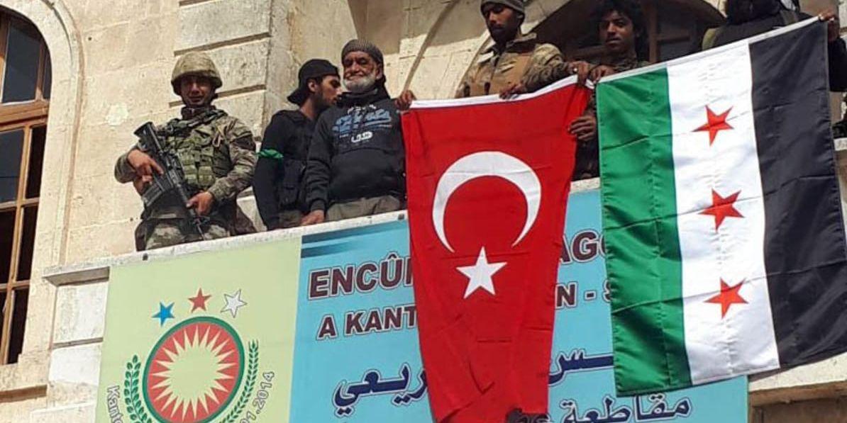 En turkisk flagga bredvid den allierade rebellgruppen Fria syriska arméns flagga i Afrins stadskärna på söndagen.
