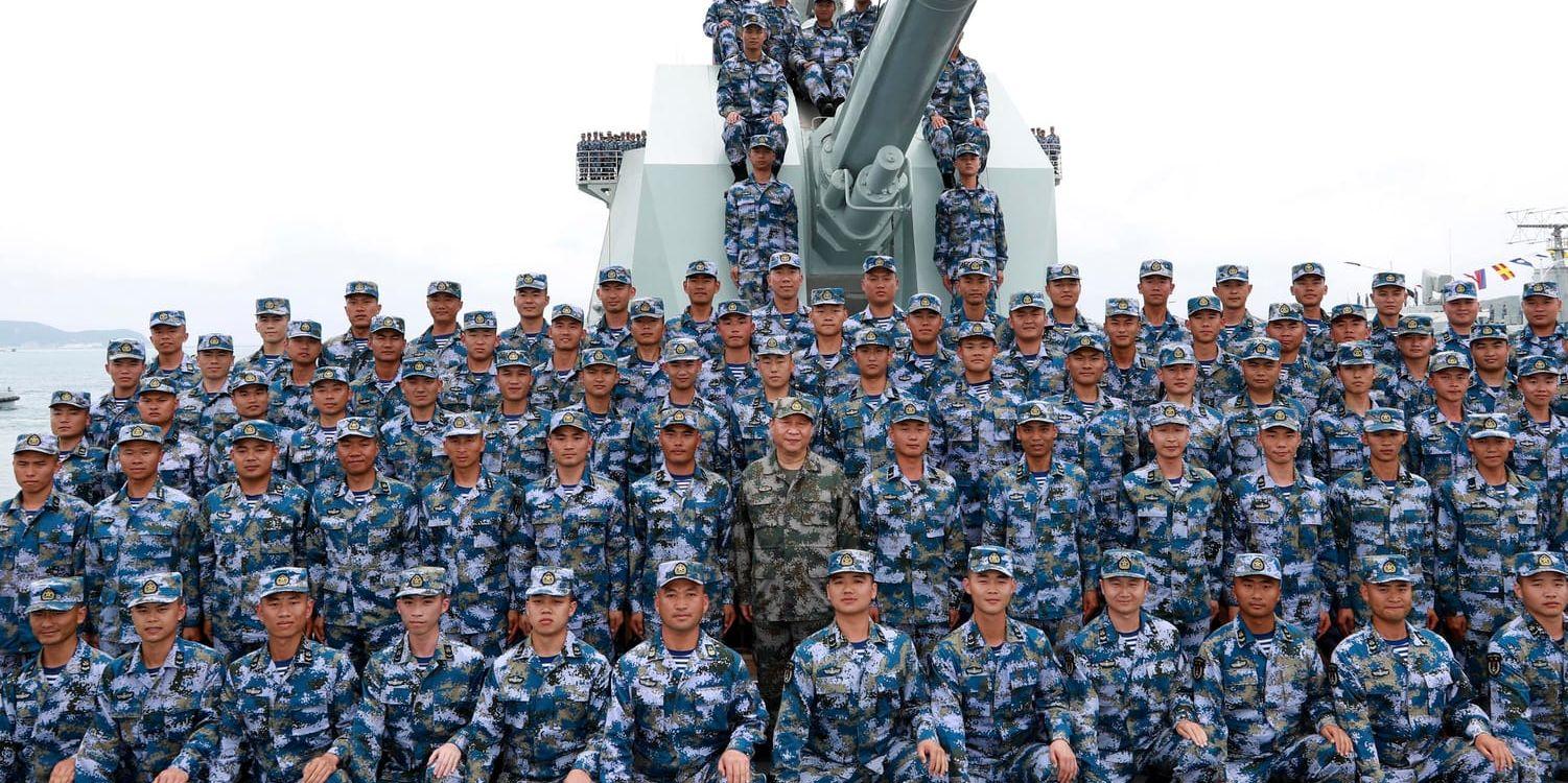 Kinas president Xi Jinping, i mitten, poserar tillsammans med soldater ombord på ett krigsfartyg. Arkivbild.