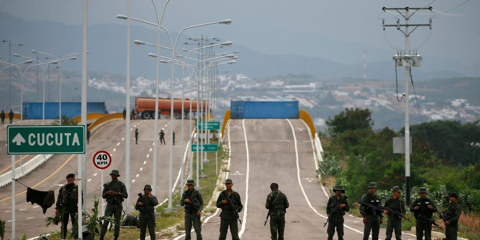 Venezuelanska soldater framför ett tankbilssläp och två stora containrar som spärrar av gränsbron över floden Táchira mellan Venezuela och Colombia.