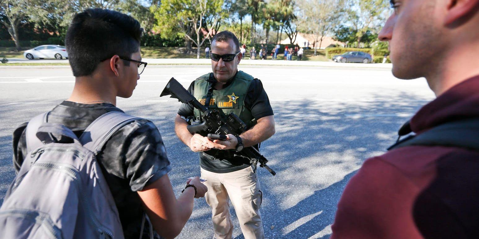 En polisman talar med elever vid skolan i Parkland i Florida efter skottlossningen.