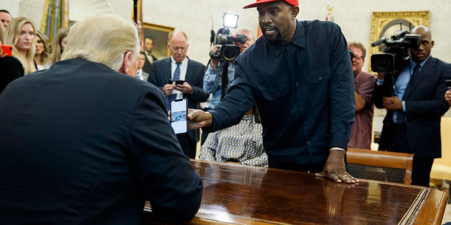 Kanye West visar USA:s president Donald Trump bilder i sin telefon under mötet i Ovala rummet.