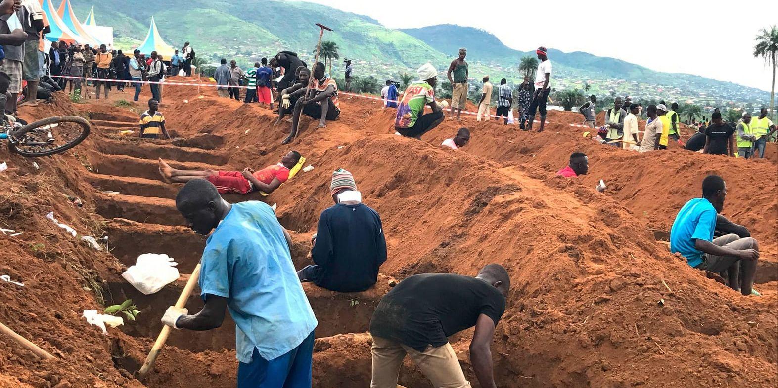 Frivillliga hjälper till att gräva gravar under en massbegravning av offren för jordskredet i Freetown.