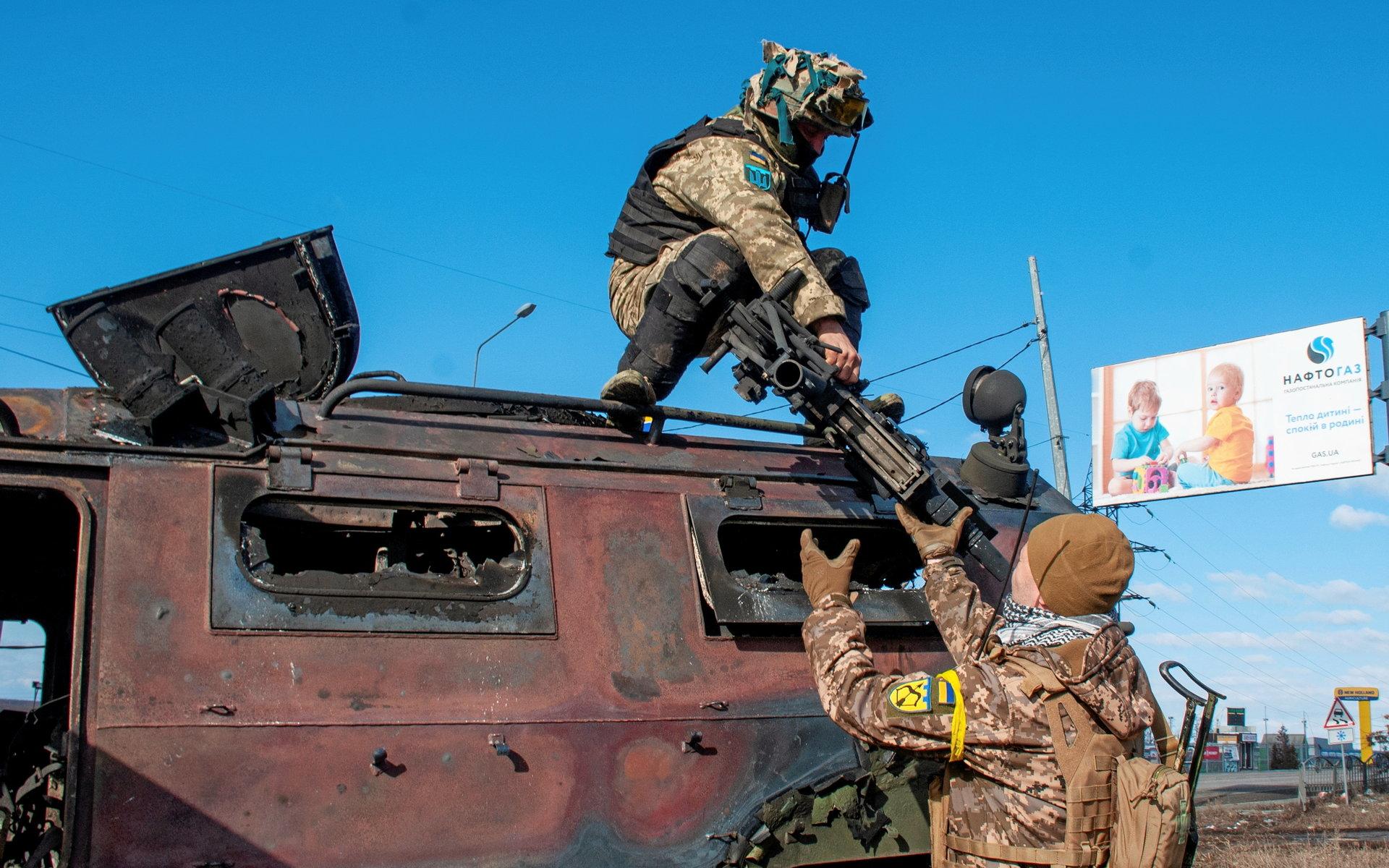 Ukrainska soldater inspekterar här ett ryskt pansarfordon som slagits ut och brunnit.