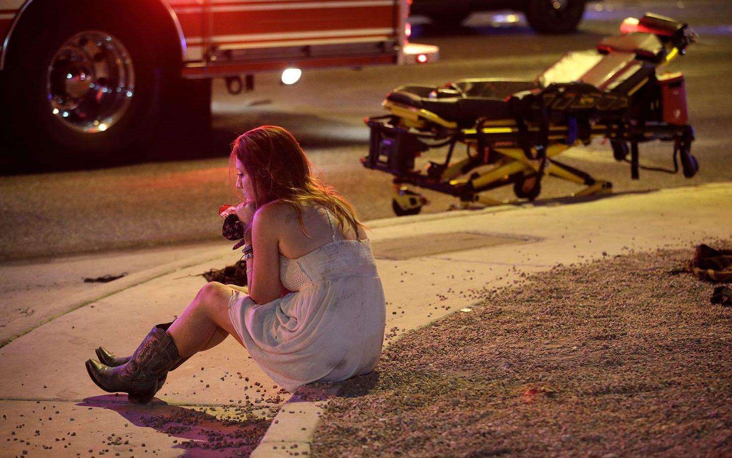 En kvinna sitter på gatan efter masskjutningen. FOTO: AP
