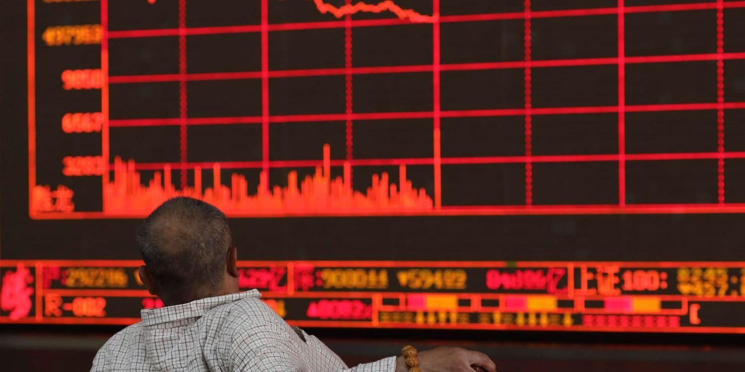 En kinesisk investerare betraktar Shanghais kompositindex som föll kraftigt under måndagen efter Trumps hot om höjda handelstullar mot Kina.