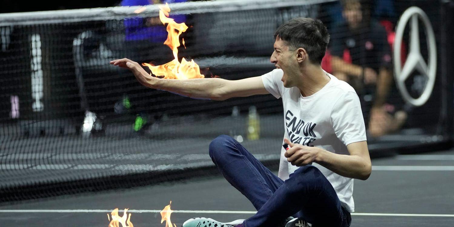 En man sätter eld på sin egen arm i protest mot privatflygen i Storbritannien.