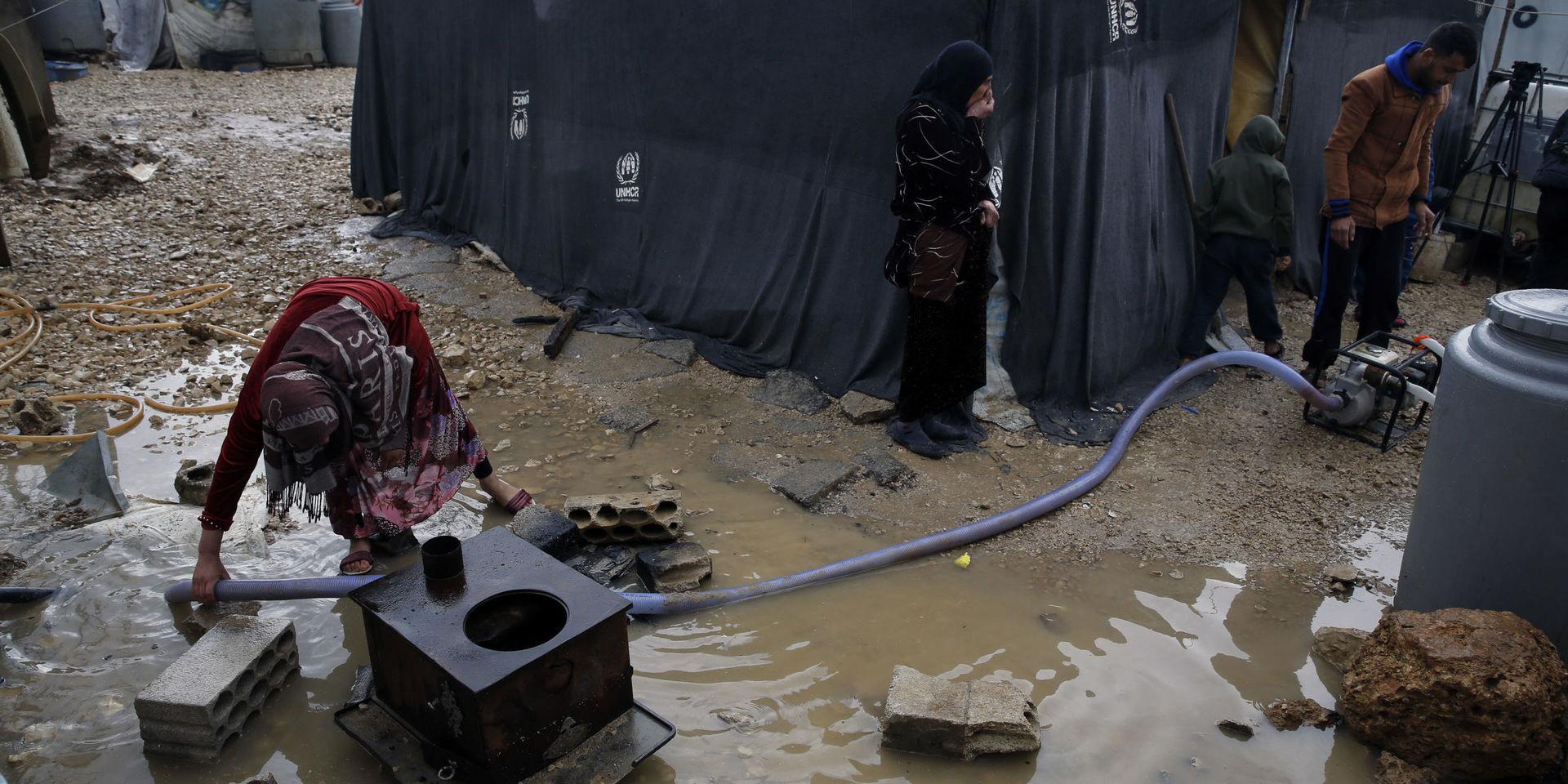 En flyktingfamilj pumpar bort vatten i ett flyktingläger i Bekaadalen i Libanon efter kraftiga regn i januari i fjol. Arkivbild. 