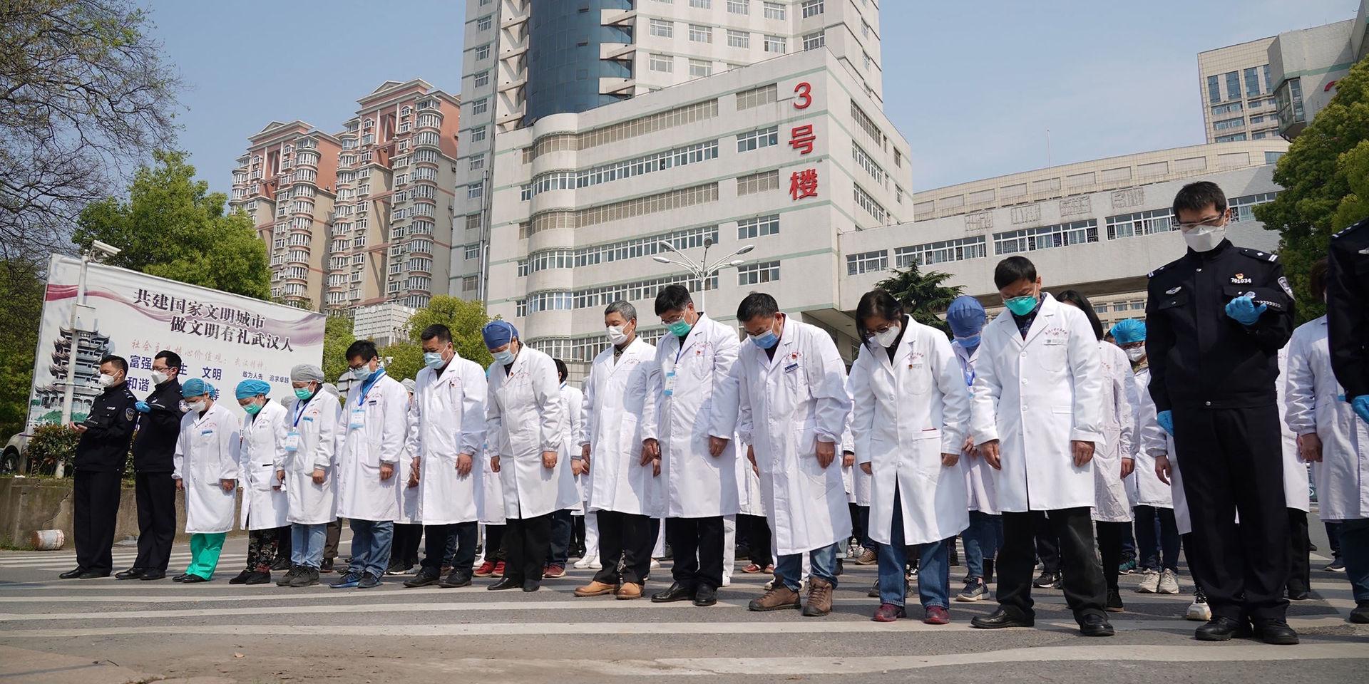 Sjukvårdspersonal i Wuhan under lördagens minnesstund. 