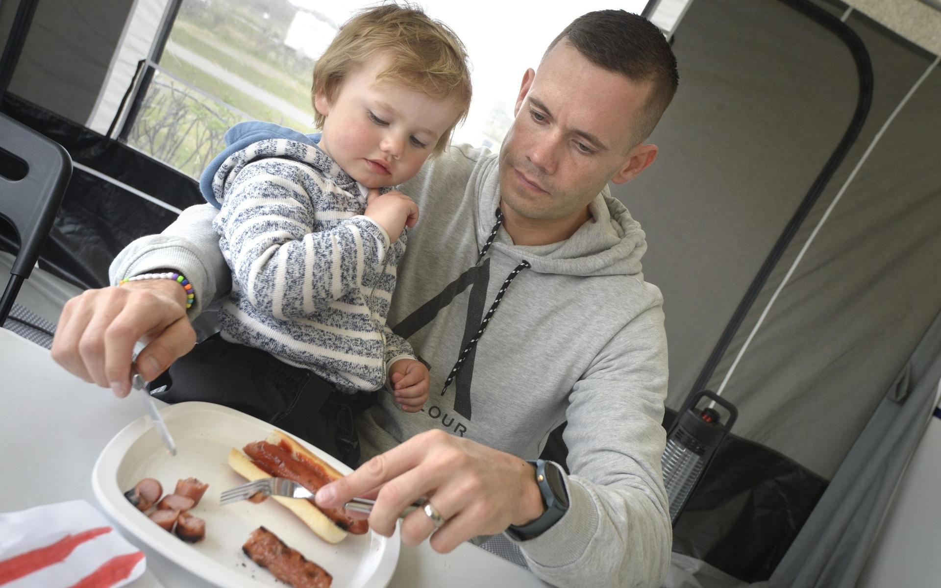 Johan Askman utfodrar familjens minste, William, med en hot dog.
