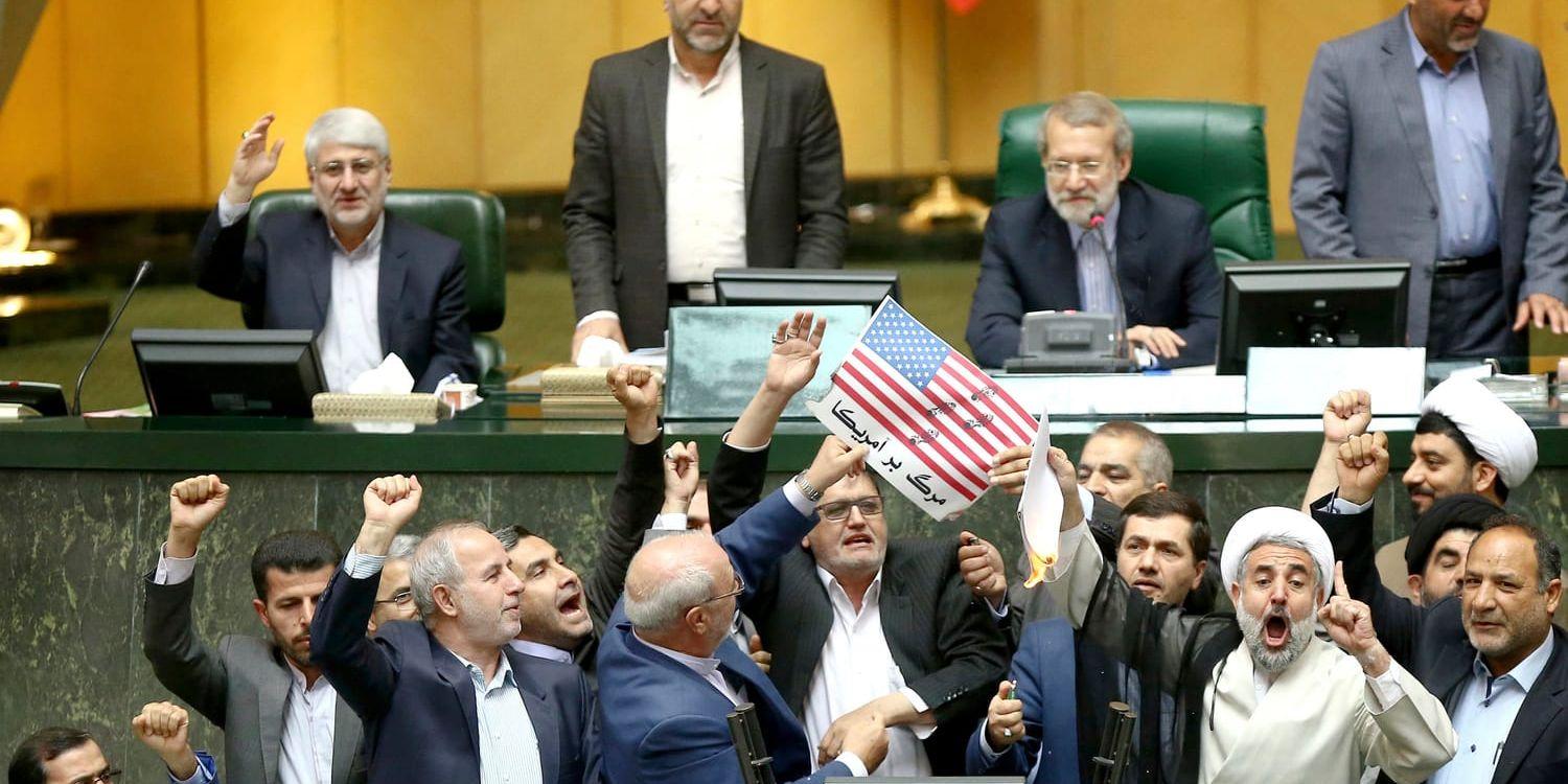 Iranska politiker bränner två pappersbitar som ska representera den amerikanska flaggan och kärnenergiavtalet i parlamentet i Teheran.
