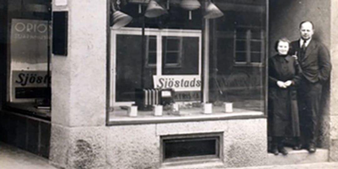 Ragnar Sjöstad tillsammans med en anställd utanför butiken på Sundsgatan 13 i Vänersborg 1936, samma år som butiken öppnades.