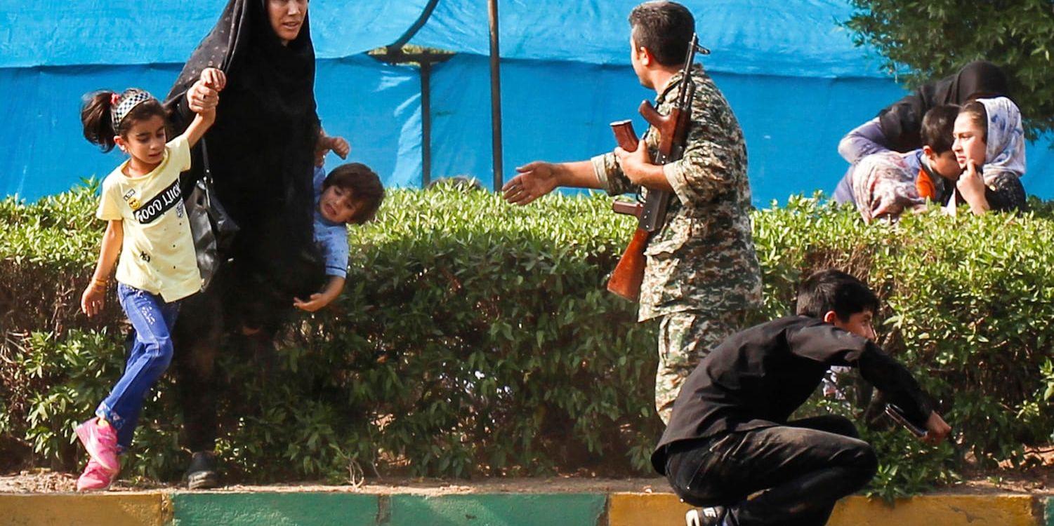 En kvinna och hennes barn tar skydd medan en soldat försöker hjälpa dem under attentatet i Ahvaz, Iran.