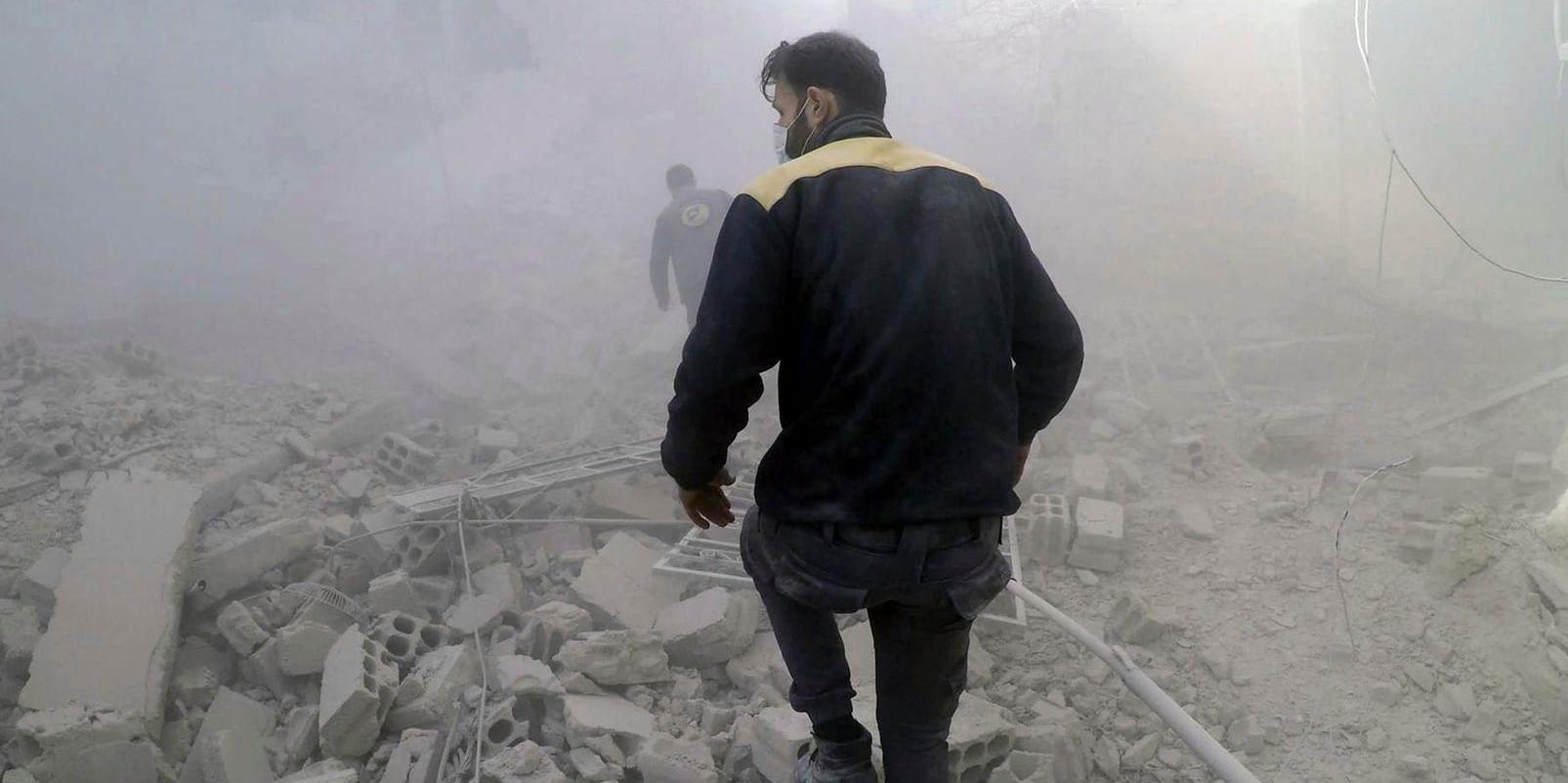 Räddningsarbetare letar efter överlevande efter en flygräd mot en rebellkontrollerad förort till Damaskus i Syrien. Bilden är från i torsdags.