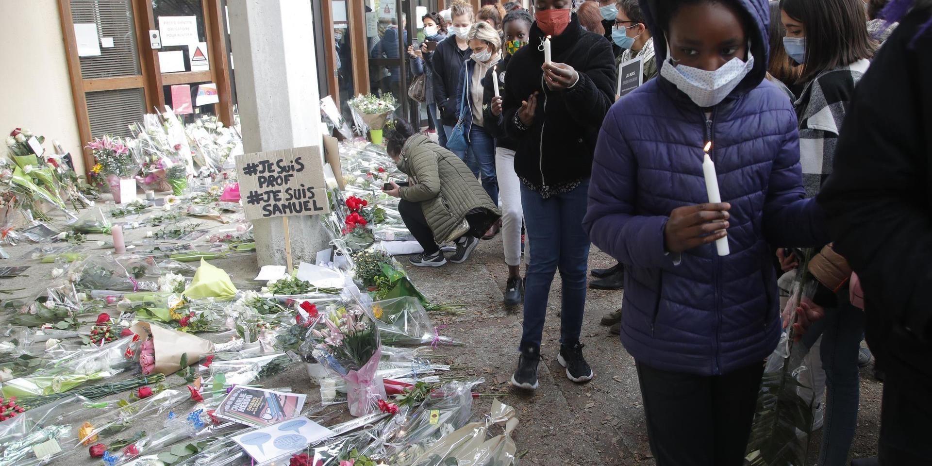 Blommor och tända ljus utanför skolan i Parisförorten Conflans-Sainte-Honorine, där en lärare mördades i fredags.