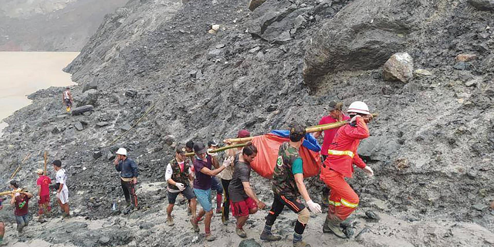 Räddningsarbetare bär en omkommen gruvarbetare efter jordskredet i delstaten Kachin. 