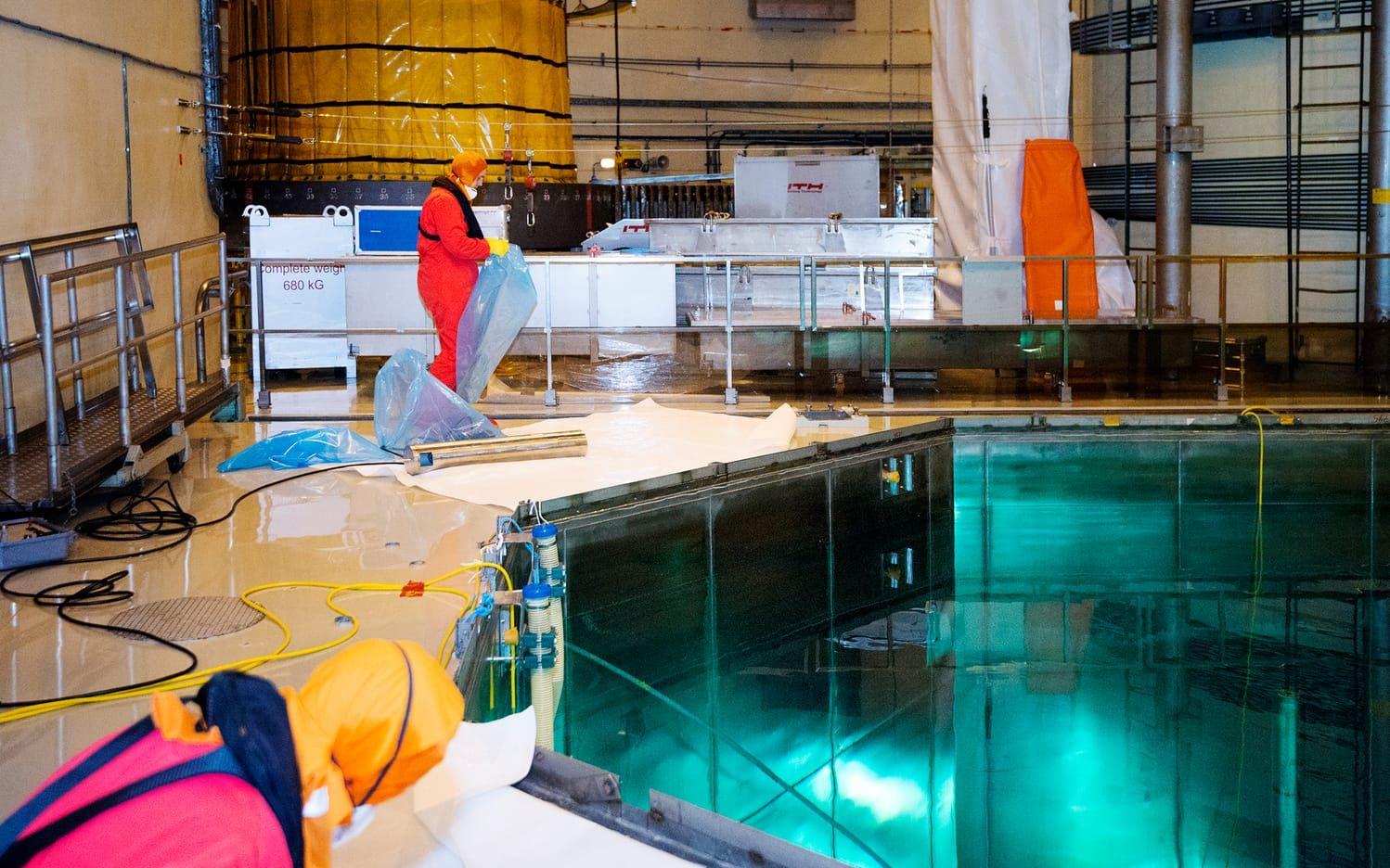 I reaktorhallen med bassängen som är så nära vi kan komma reaktorhärden. Personal i röda overaller har tillträde till FME-området för sanering.