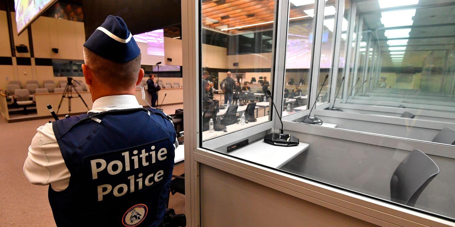 En polisman står invid de glasburar för anklagade i terrorrättegången i Bryssel. Glasburarna byts efter klagomål från försvaret ut och nu har rättegångsstarten försenats flera veckor. Arkivbild.