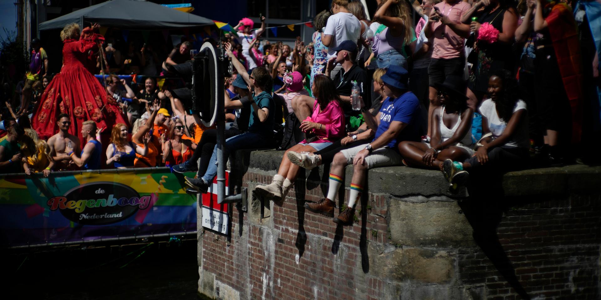 Hundratusental människor beräknas ha samlats på broar och längs kanaler för att följa Amsterdams färgsprakande flytande prideparad.