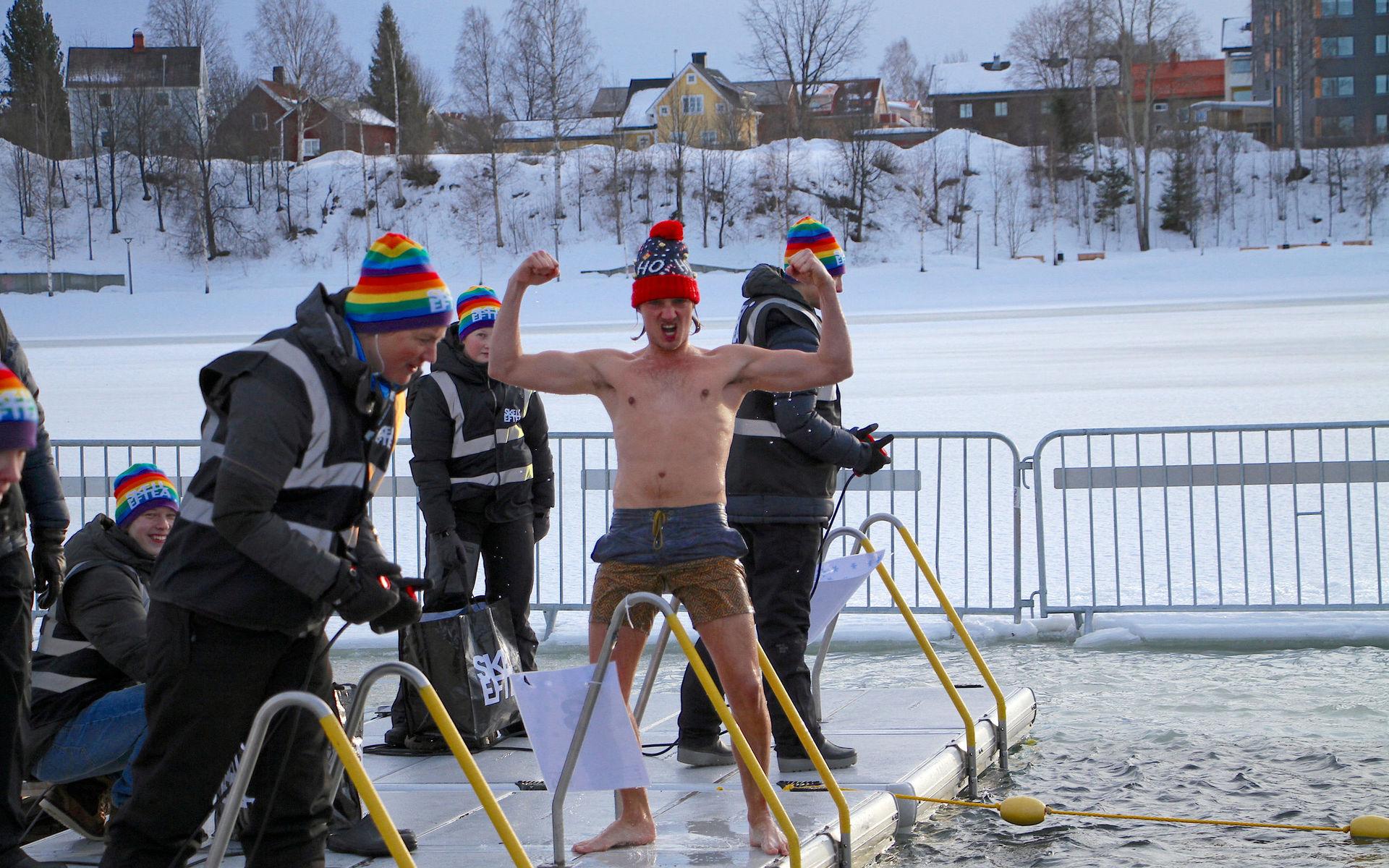 Pontus Johansson jublar efter målgången, medan de väl påpälsade funktionärerna inväntar de övriga deltagarna i heatet. Vintersimmet i Skellefteälvens februarikalla vatten lockar allt fler deltagare.