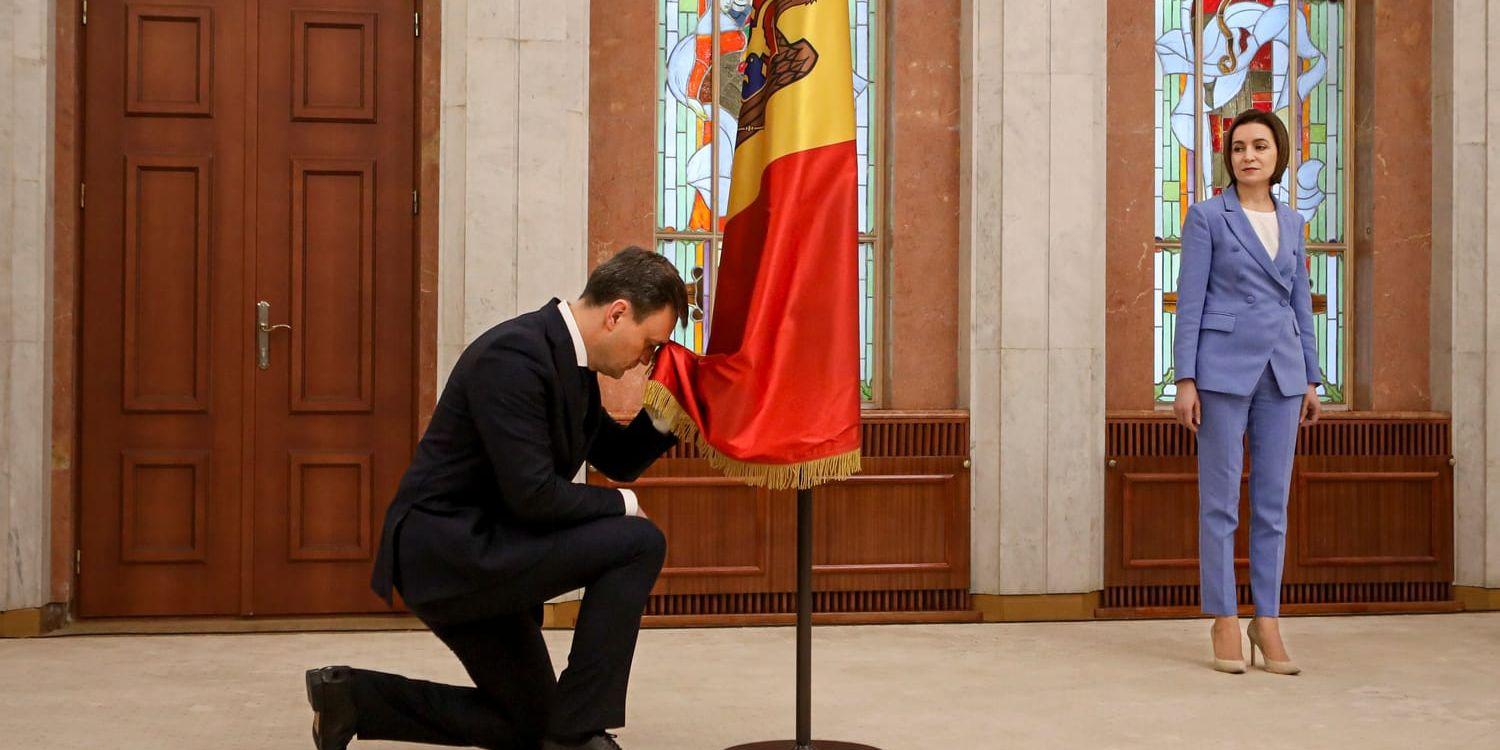 President Maia Sandu ser på när nytillträdde premiärminister Dorin Recean bugar inför den moldaviska flaggan den 16 februari. Recean fick posten för att hantera det ökade säkerhetshotet.
