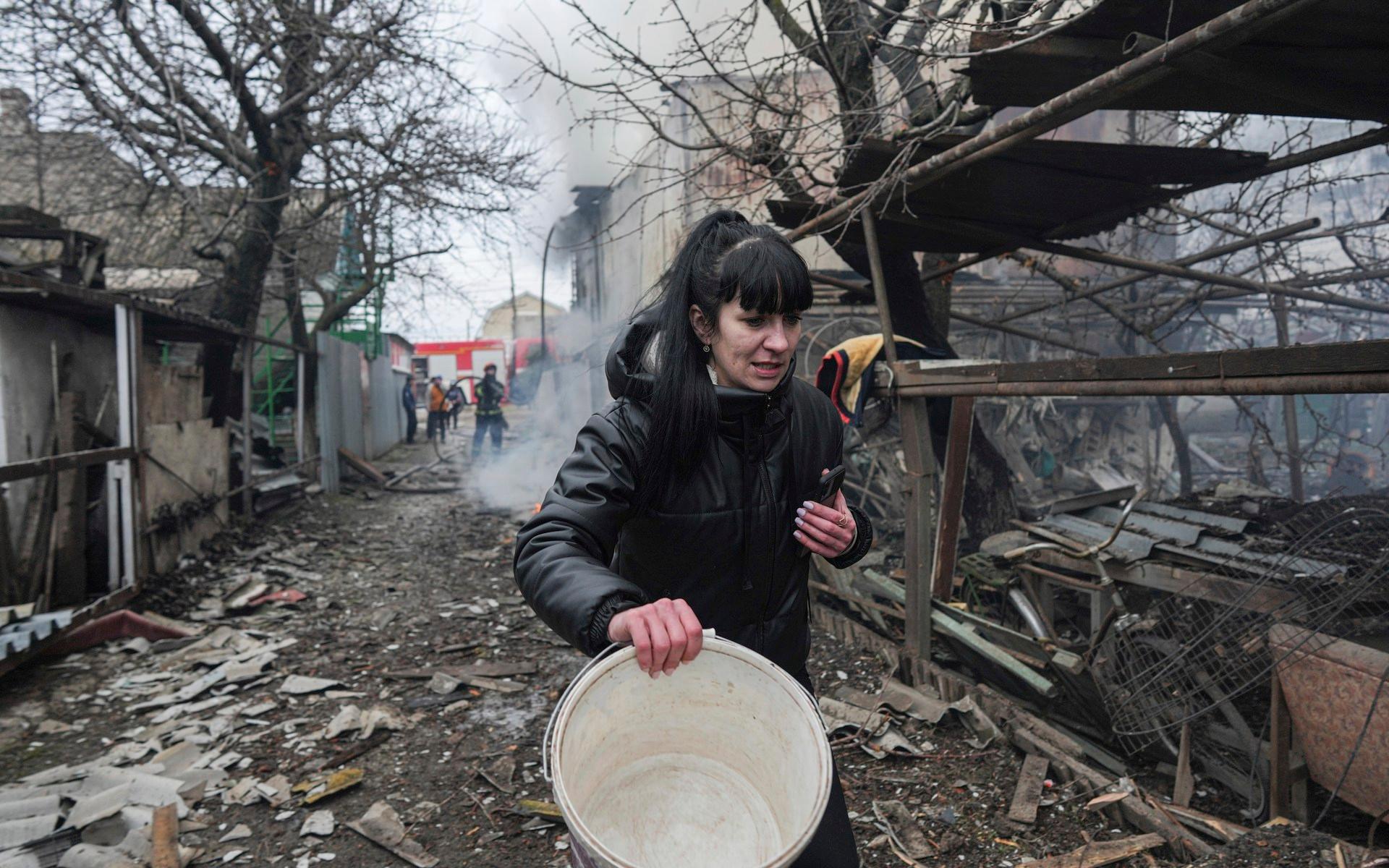  En kvinna i ukrainska Mariupol går längs gatan med det redan syns spår från dagens explosioner.