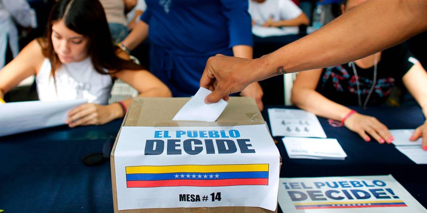 En man i Caracas röstar i oppositionens informella folkomröstning. Texten på valurnan lyder: "Folket bestämmer."