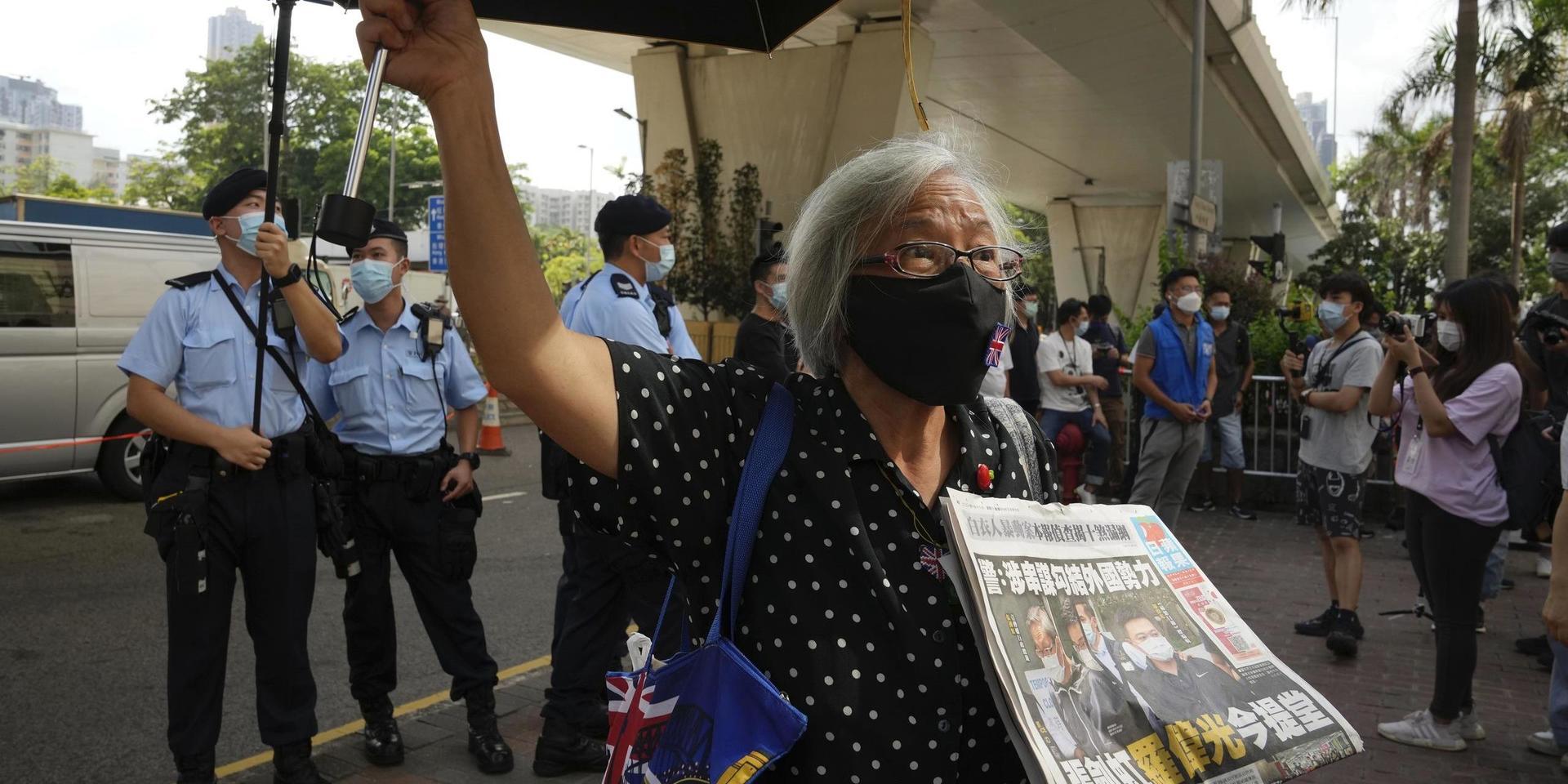 En demokratiaktivist med ett exemplar av Apple Daily utanför en domstol i Hongkong.