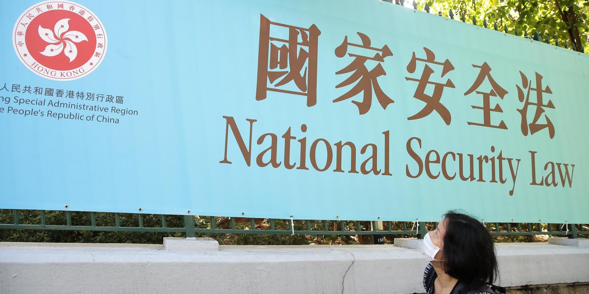 En kvinna går förbi en reklamskylt för Kinas nya säkerhetslag för Hongkong, som innebär att Hongkongbor kan straffas under kinesiska lagar.