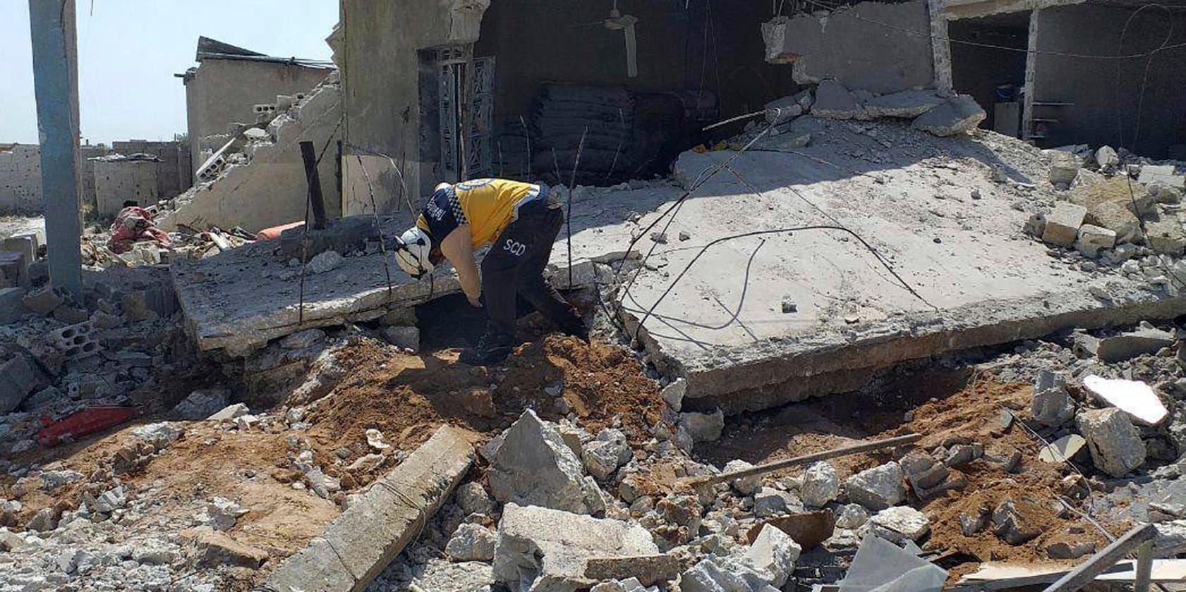 En hjälparbetare från den syriska civilförsvarsgruppen Vita hjälmarna söker i rasmassor av ett hus som träffats i ett luftanfall i en by i Idlib. Bilden är tagen på tisdagen och distribuerad av Vita hjälmarna.