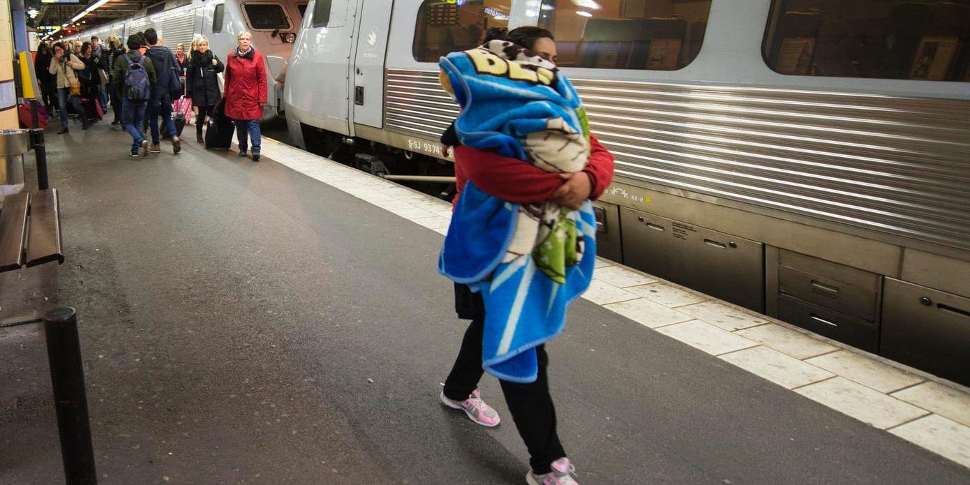 En kvinna med ett sovande barn anländer till Stockholm med tåget från Malmö/Köpenhamn under hösten 2015, då många flyktingar kom till Sverige. Arkivbild.