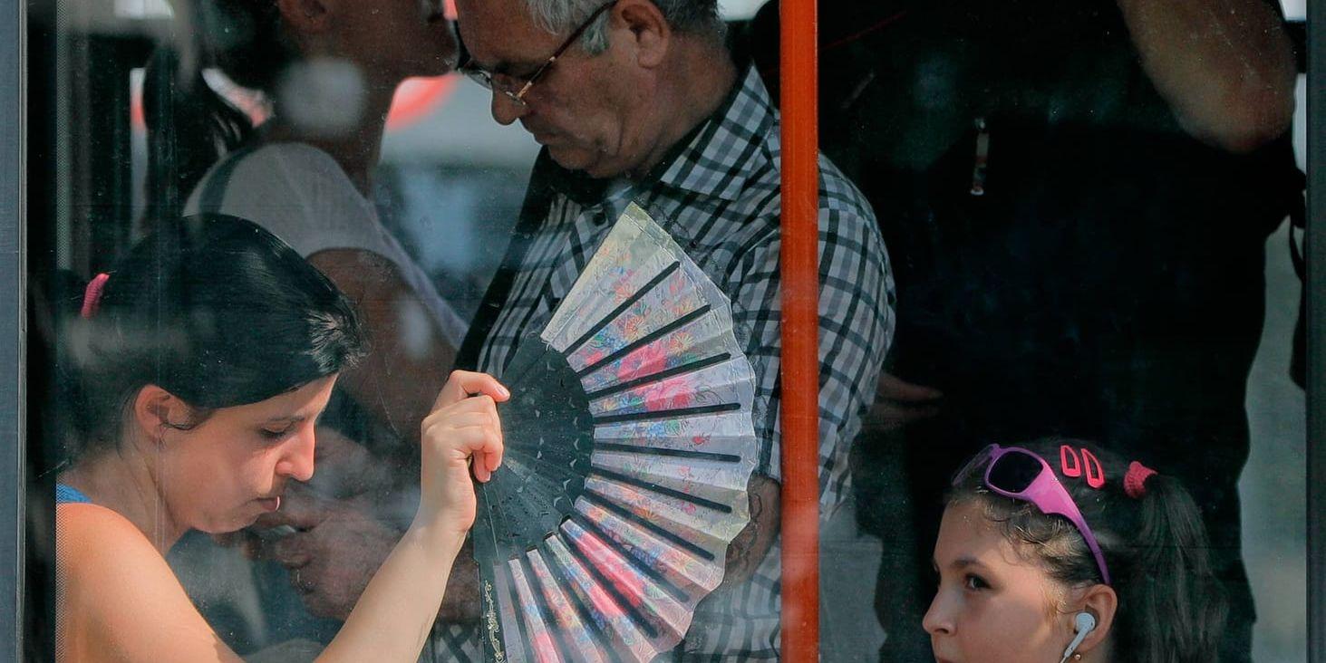 En kvinna fläktar sina barn med solfjäder på en buss i Rumänien, där värmeböljan slagit till.