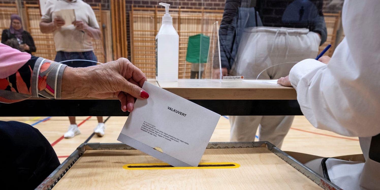 Ett valkuvert med en röst i riksdagsvalet läggs i valurnan.