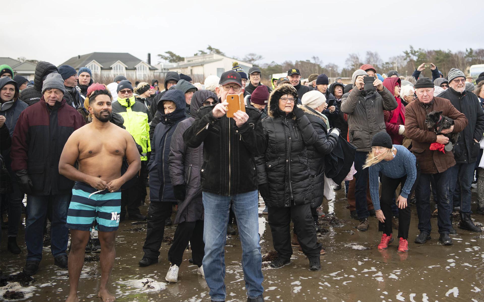 Runt 150 personer hade sökt sig ner till den blåsiga stranden för att bevittna invigningen. Till vänster syns Daniel Sanjay ladda för ett invigningsbad.