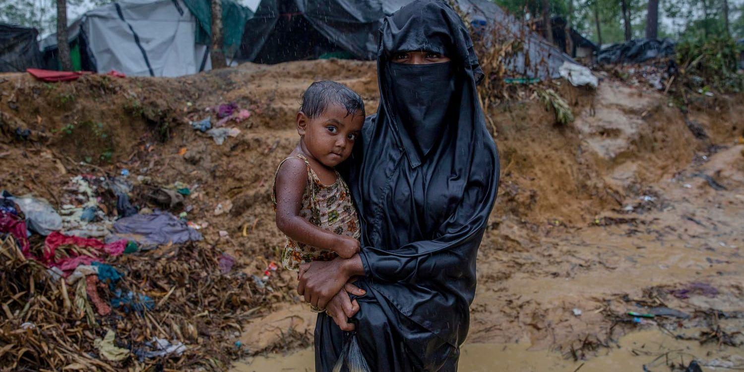 Shara Begum håller sin dotter Murad Jan utanför flyktinglägret Bulukhali, där regnet förvandlat marken till lervälling.