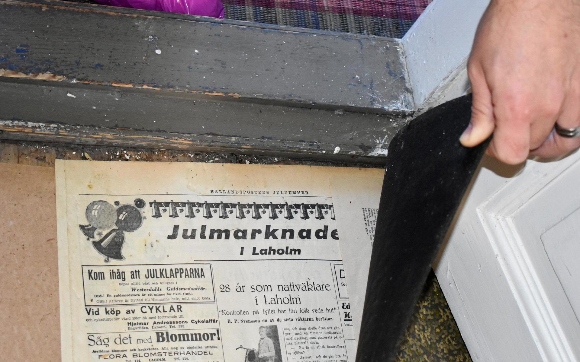 Mäklaren Fredrik Abrahamsson lyfter på golvmattorna i entrén. Här finns det riktiga ”guldfynd”, nämligen gamla Hallandsposten. Troligtvis från tiden då huset byggdes.