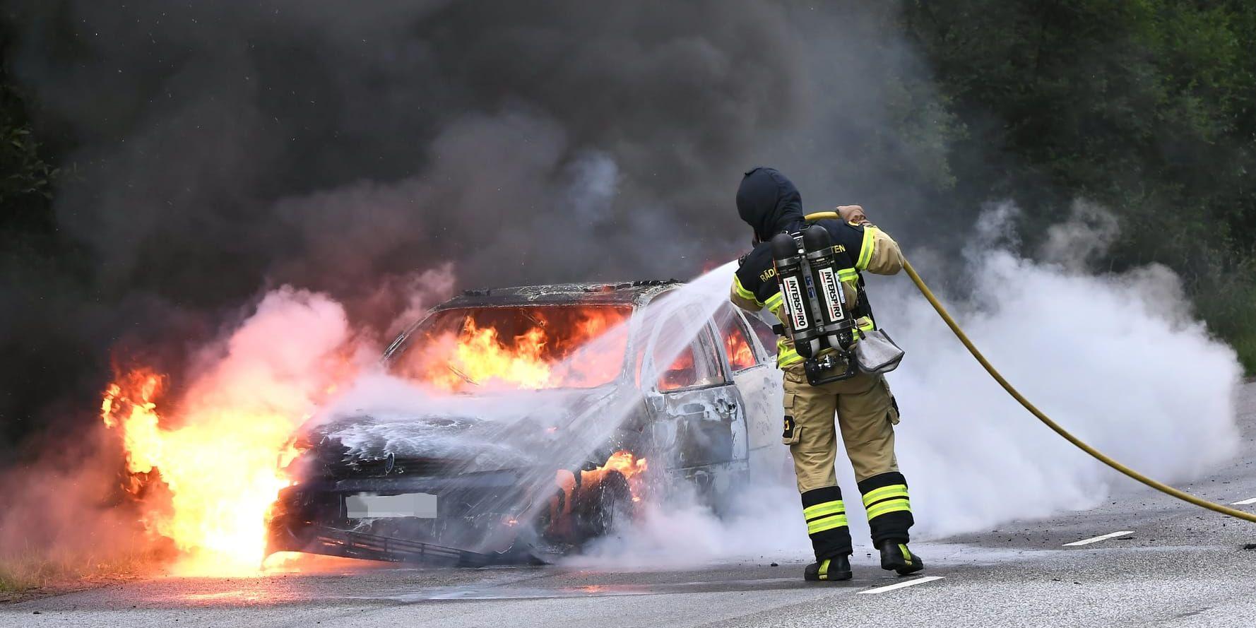 Räddningstjänstpersonal släcker en brinnande bil. Arkivbild.