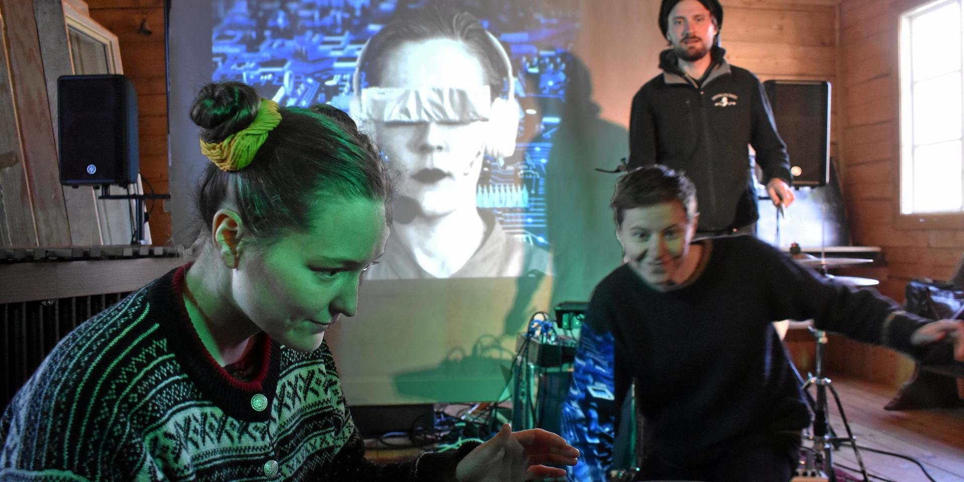 Gruppen improviserar kring en scén där de med hjälp av en bronsgong får kontakt med en artificiell varelse, som också projiceras på filmduken. Från vänster Fia Forslund, Izabelle Norén och Jonathan Kabell.
